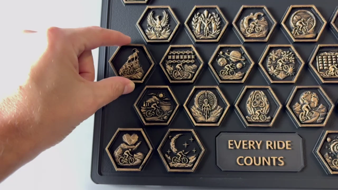 Hand placing a Cycling achievement piece onto the physical Hexonumia display